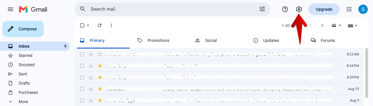 Gmail inbox with an arrow pointing at the gear icon in the top right corner